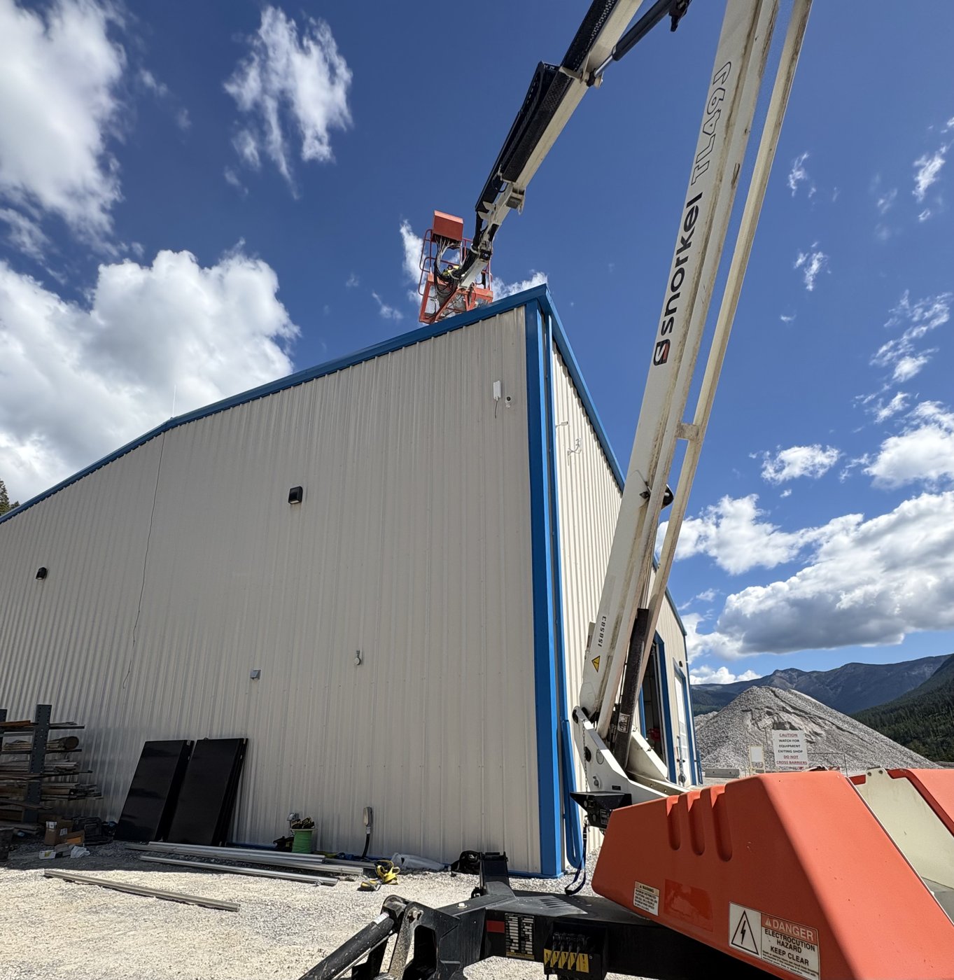 Snorkel boom lift fully extended alongside a commercial building