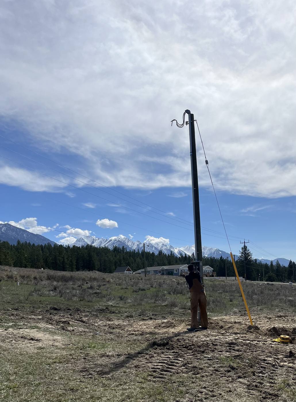 Taynton Bay Electrical crew setting a power pole with the Rocky Mountains behind, near Invermere BC