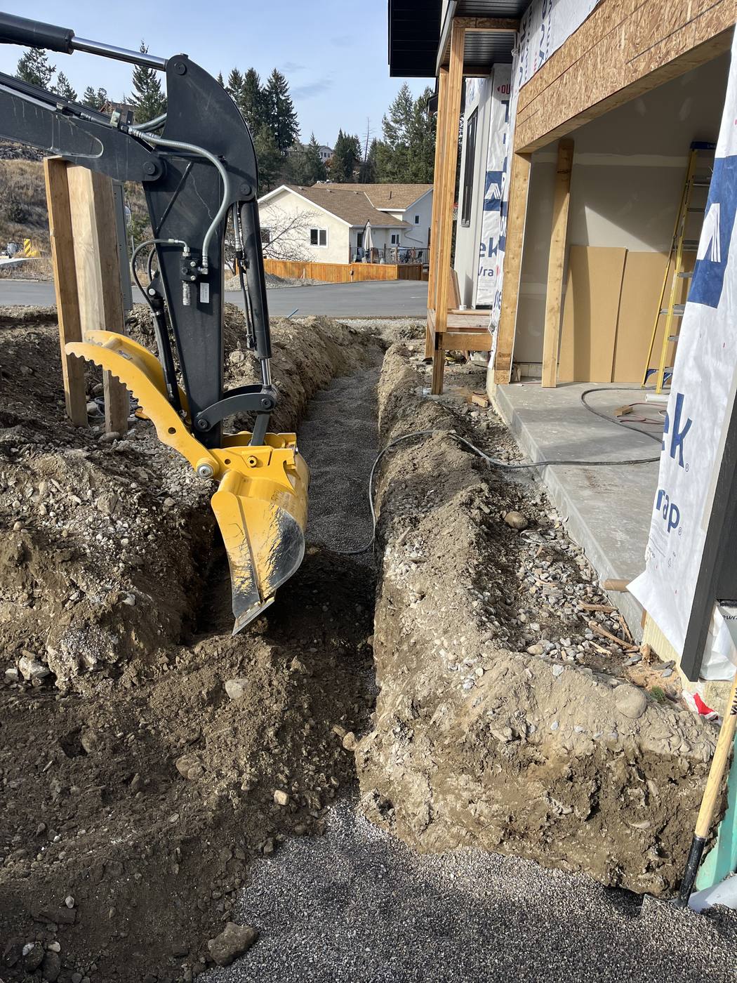 Taynton Bay Electrical mini excavator trenching beside a new home foundation